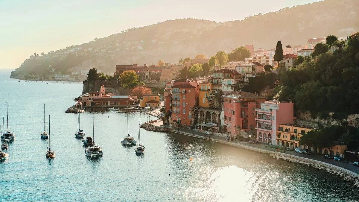 Illustration af Cote d'Azur med azurblåt hav, kystby og grønne bakker